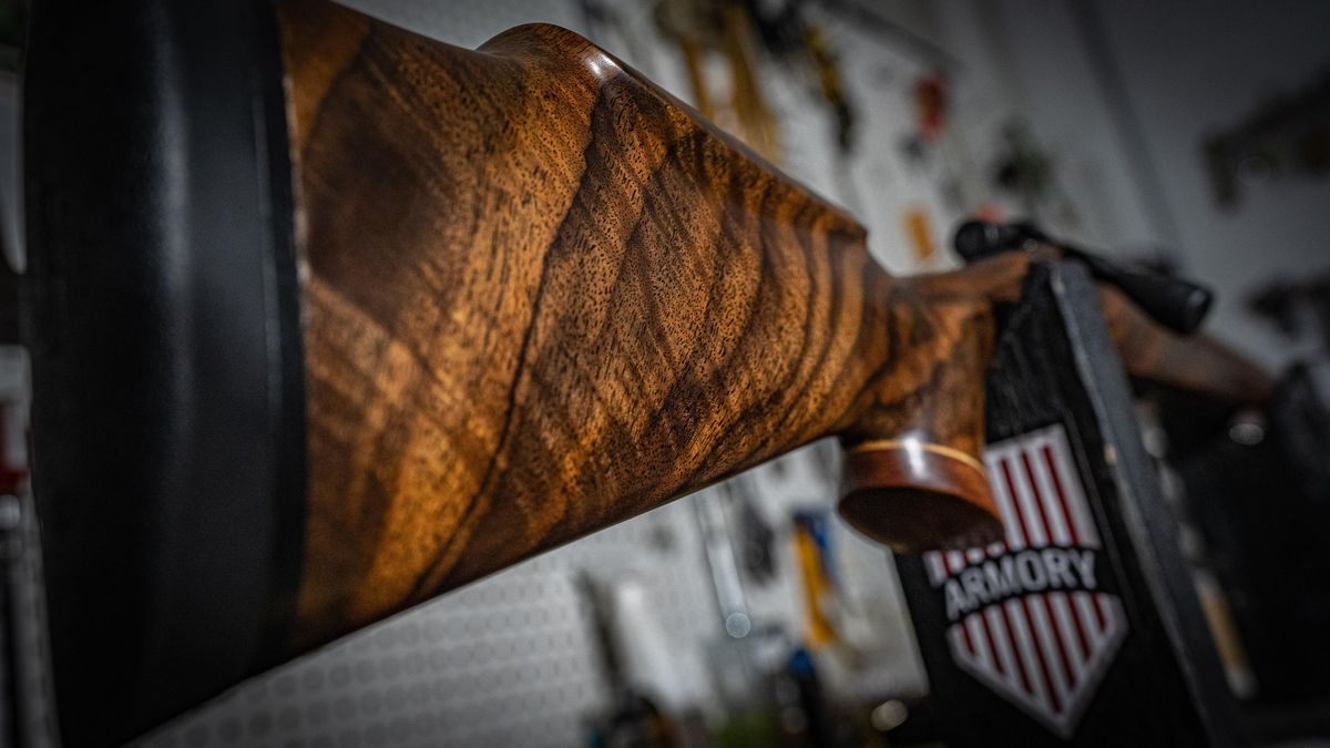 Figured walnut stock on a custom rifle, set on a 717 Armory display stand