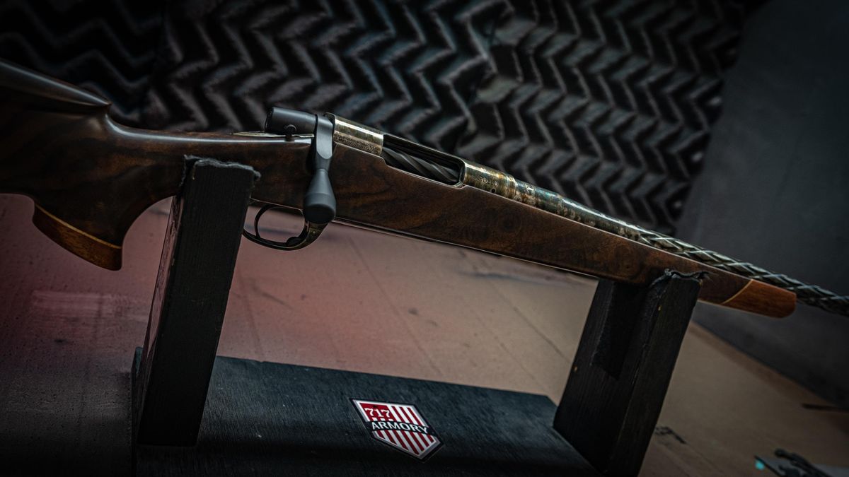 Custom rifle with a walnut stock and fluted barrel on a 717 Armory display stand