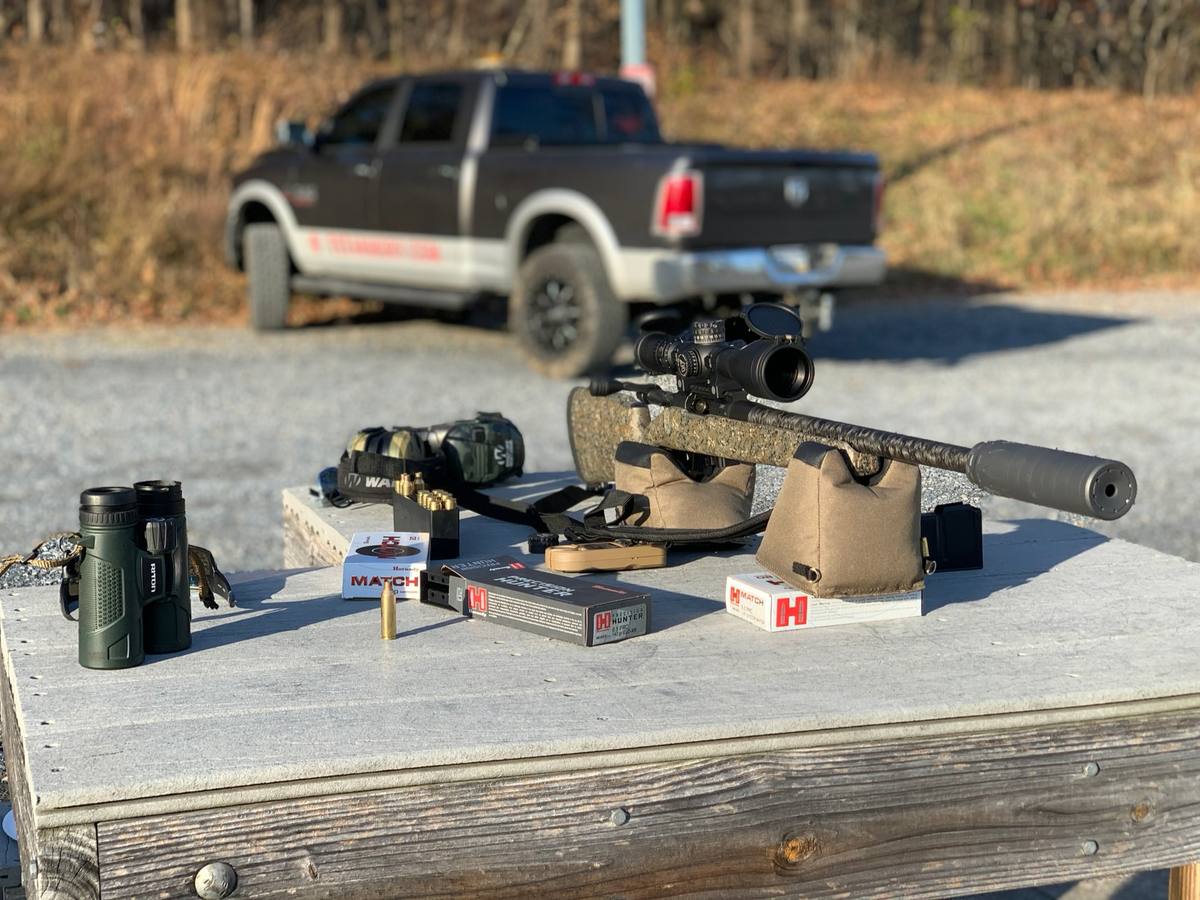 Custom rifle with a suppressor set up on an outdoor shooting bench